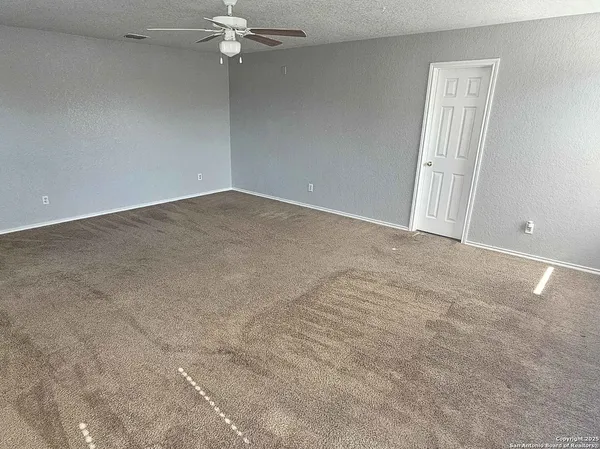 an empty room with a chandelier fan and windows