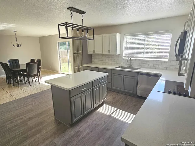 a kitchen with stainless steel appliances granite countertop a kitchen island a stove a sink a dining table and chairs