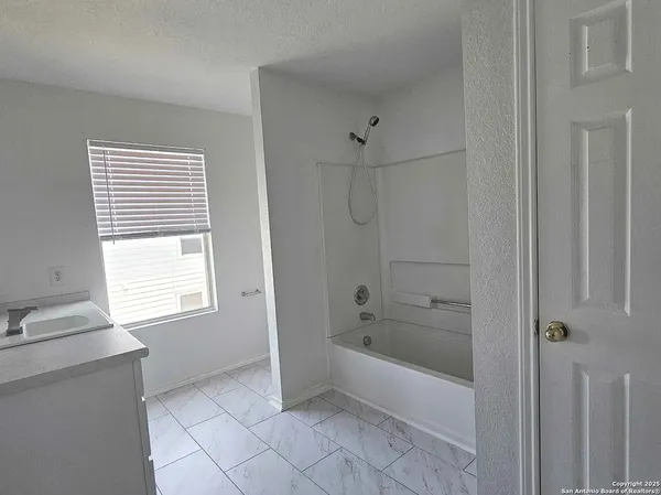 a bathroom with a bathtub a shower and a window