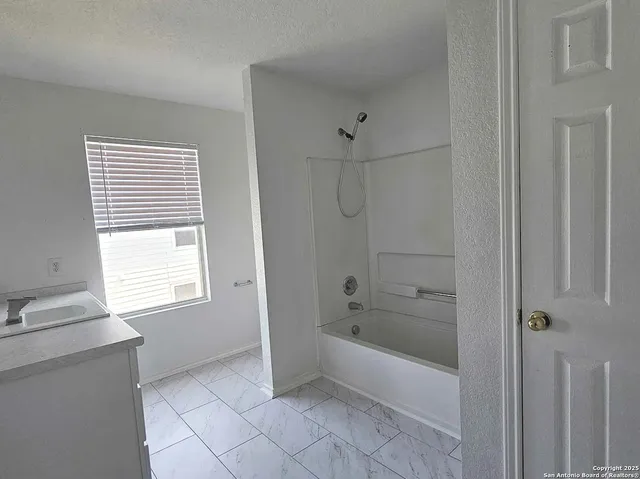 a bathroom with a bathtub a shower and a window