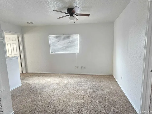 an empty room with windows and fan
