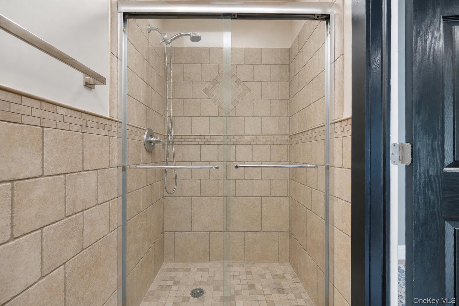19 Joan Road Bay Shore, NY 11706 - Photo 24 of 50 Tiled shower stall featuring clear glass enclosure with brushed nickel hardware, a decorative wall tile band, and a matching tiled shower pan