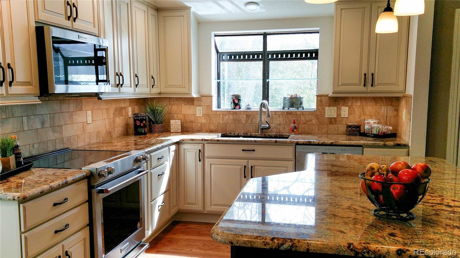 8908 Jellison Court Westminster, CO 80021 - Photo 5 of 17 a kitchen with stainless steel appliances granite countertop a stove a sink and a microwave