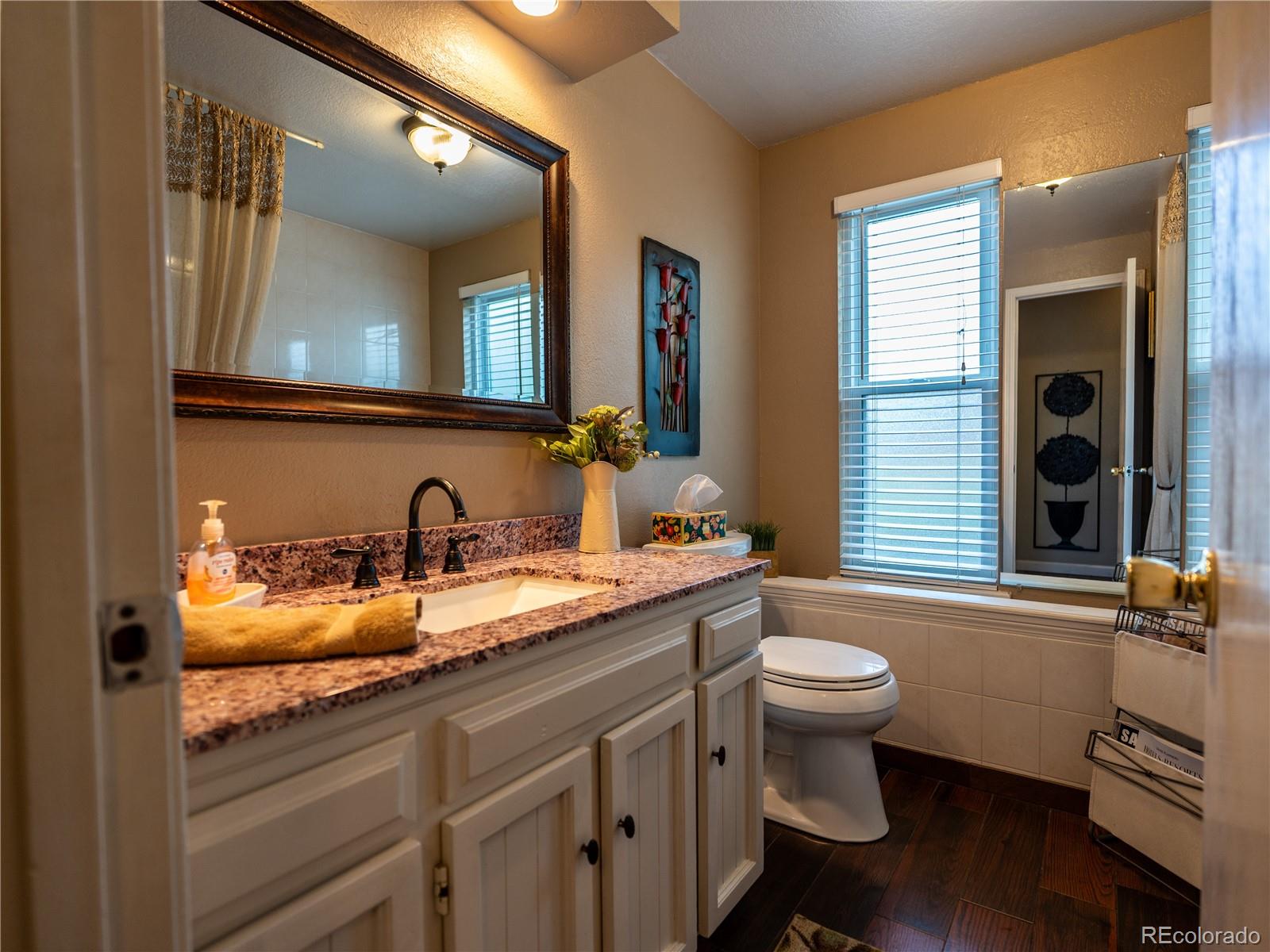 8908 Jellison Court Westminster, CO 80021 - Photo 7 of 17 a bathroom with a granite countertop sink a toilet a mirror and a window