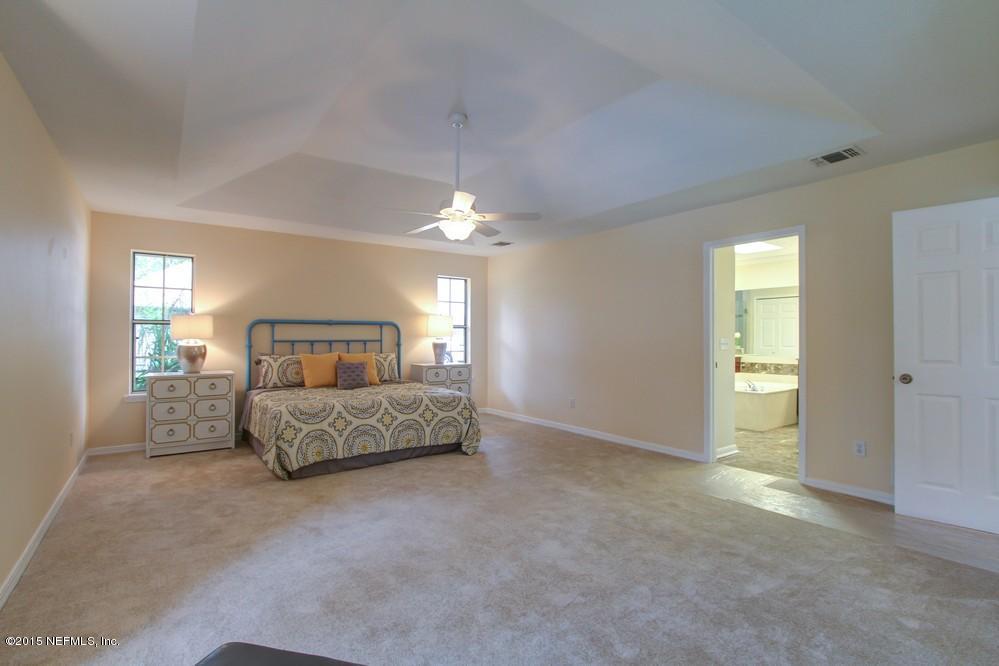 3038 Nautilus Road Middleburg, FL 32068 - Photo 19 of 45 a spacious bedroom with a bed and a chandelier
