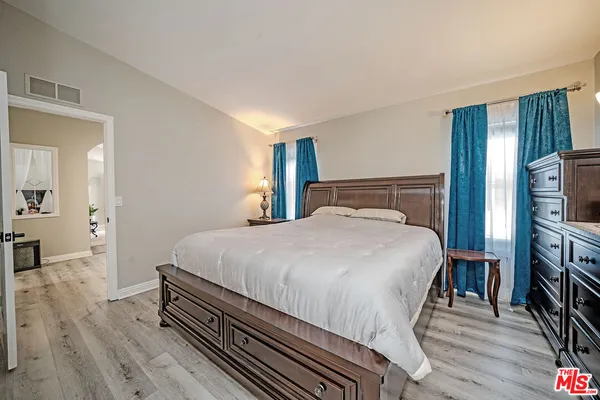 a bedroom with a bed and a flat tv screen on a dresser