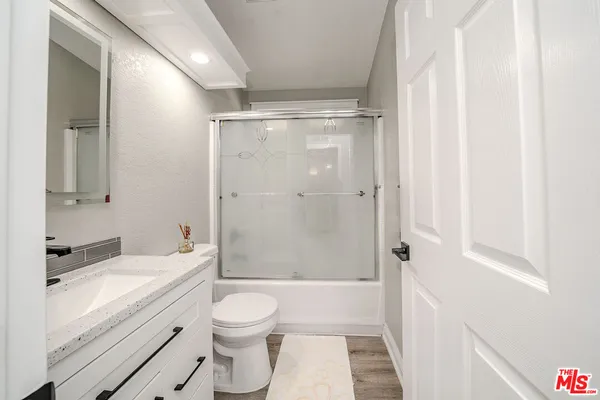 a bathroom with a granite countertop sink toilet and shower