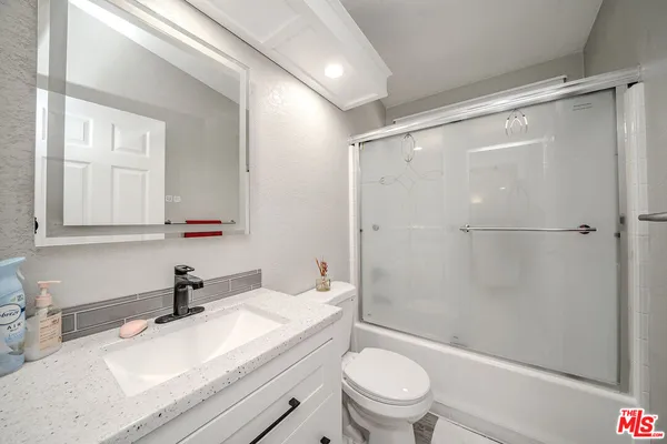 a bathroom with a granite countertop sink toilet and shower