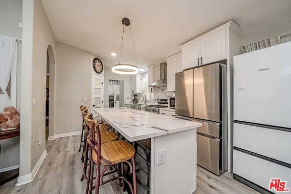 a kitchen with stainless steel appliances a refrigerator a sink a stove a dining table and chairs