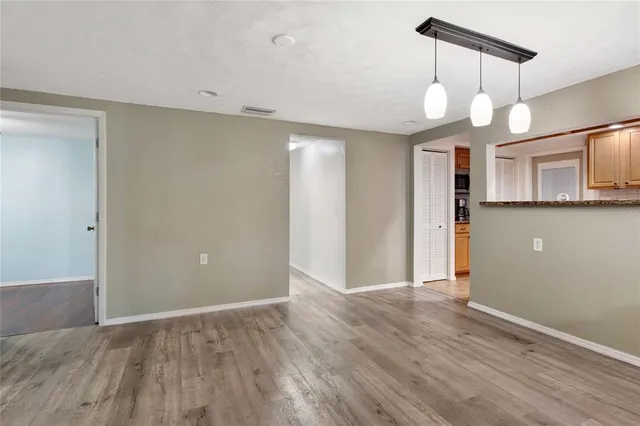 an empty room with a chandelier fan and windows