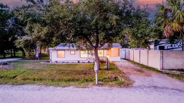 a view of a park that has large trees and a wooden fence