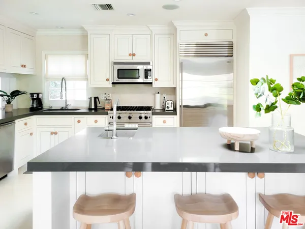 a kitchen with stainless steel appliances granite countertop a sink a stove a microwave a refrigerator and white cabinets