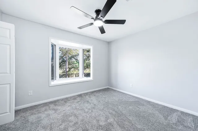 an empty room with windows and ceiling fan
