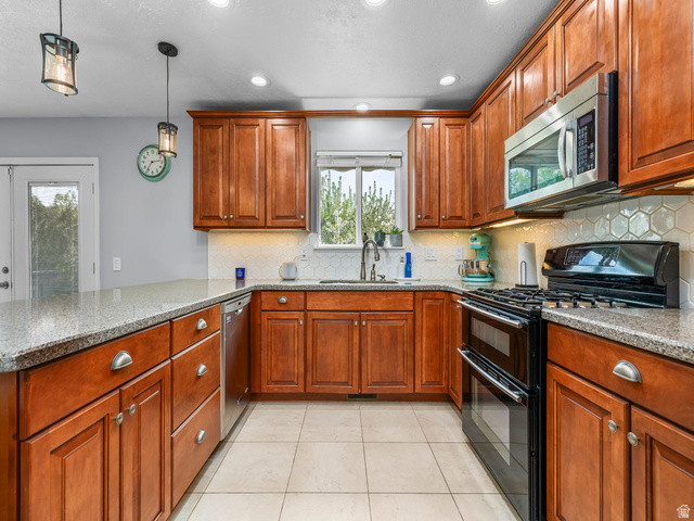 523 Mountain View Road Centerville, UT 84014 - Photo 7 of 33 Kitchen featuring stainless steel appliances, wood finish cabinets, light stone counters, a peninsula, and decorative light fixtures