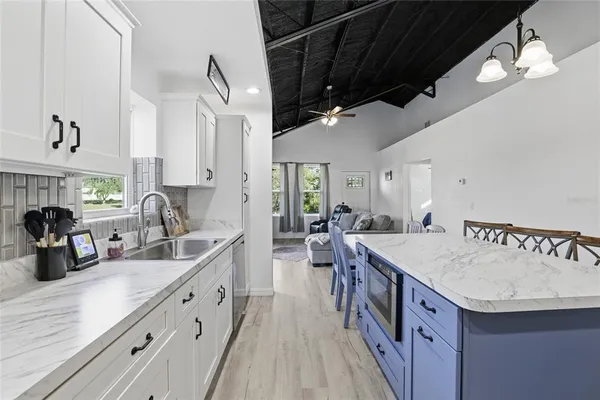 a kitchen with granite countertop a sink a counter space appliances and cabinets