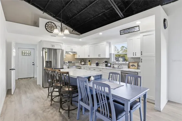 a kitchen with a dining table chairs stainless steel appliances and cabinets