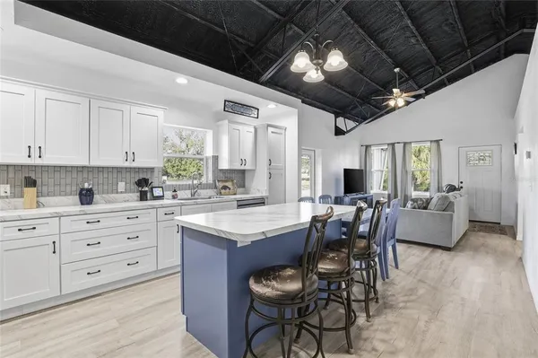 a kitchen with granite countertop lots of white cabinets stainless steel appliances dining table and chairs