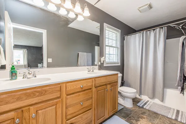 a spacious bathroom with a double vanity sink a mirror and a toilet