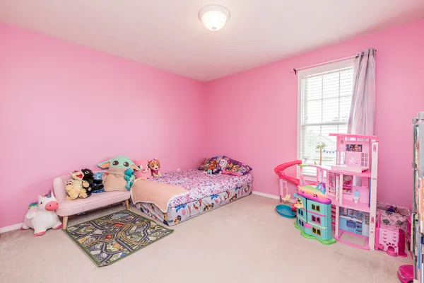a bedroom with pink bed and toys