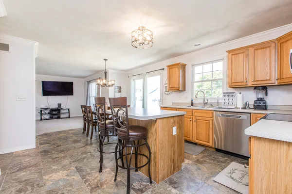 a kitchen with stainless steel appliances granite countertop a stove top oven a sink a dining table and chairs with wooden floor