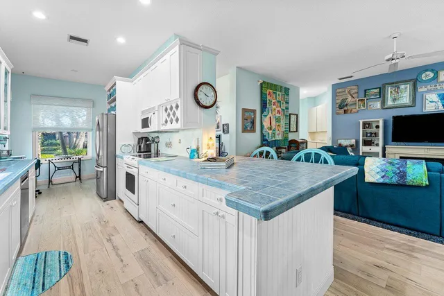 a large kitchen with a large counter space a clock and cabinets