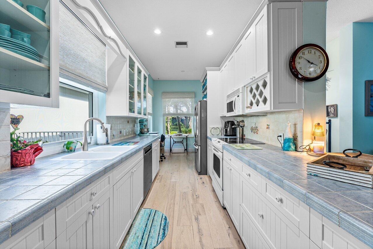 198 Hampton Circle Jupiter, FL 33458 - Photo 16 of 32 a large kitchen with a large counter space a clock and cabinets