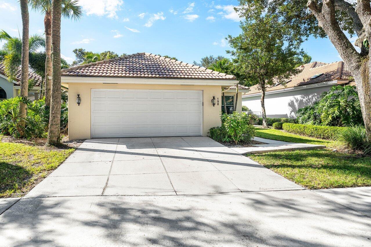 198 Hampton Circle Jupiter, FL 33458 - Photo 2 of 32 a front view of a house with a yard and potted plants