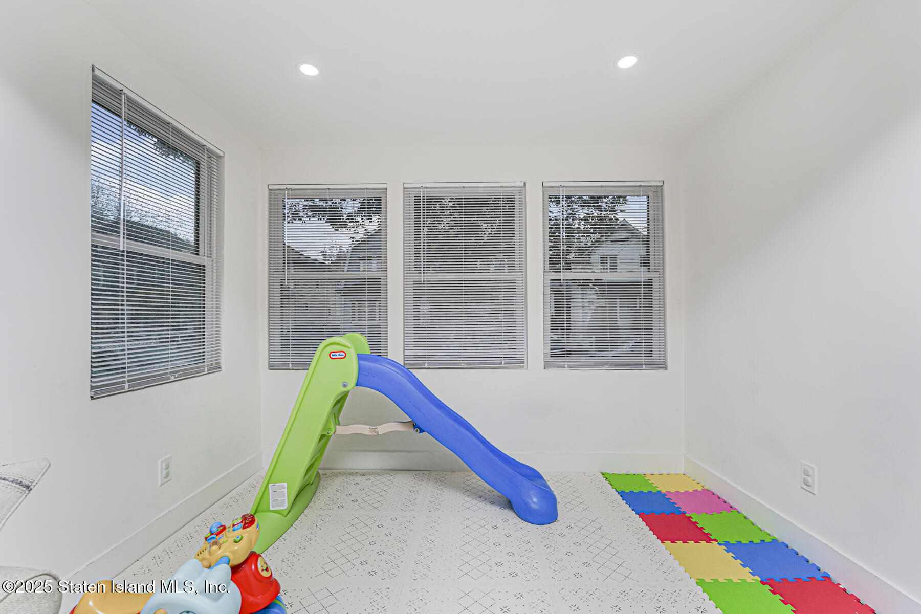 145 Clinton Place Staten Island, NY 10302 - Photo 19 of 41 a view of a living room with a baby crib and a wooden floor