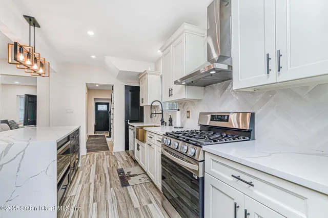 a kitchen with stainless steel appliances granite countertop a stove and a white cabinets
