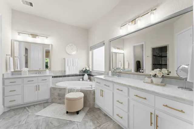 a bathroom with a granite countertop double vanity sink mirror and bathtub