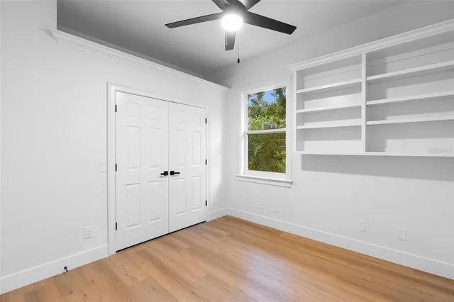 a view of an empty room with a window and wooden floor