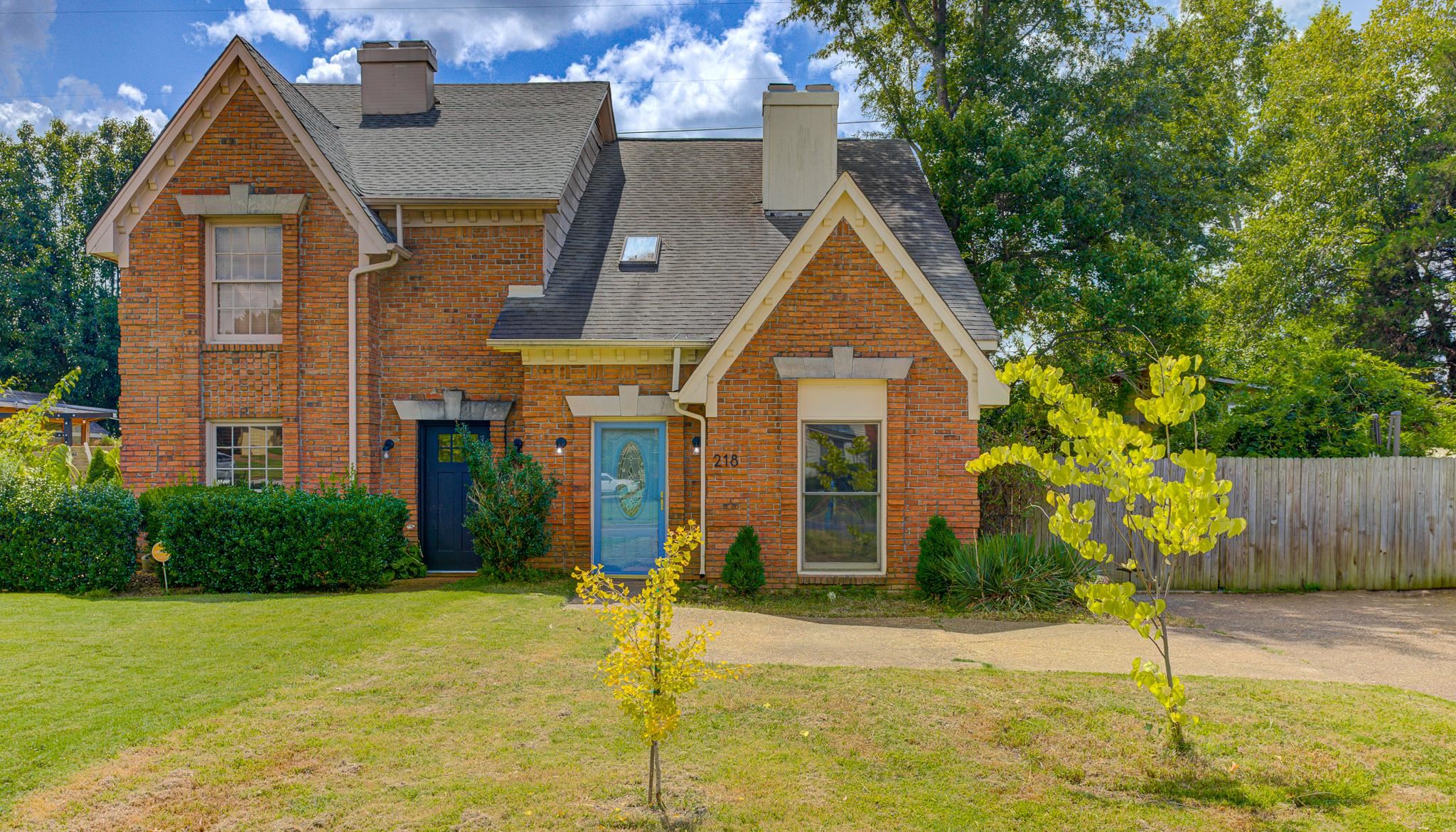 View of front facade featuring a chimney, brick siding, and a shingled roof