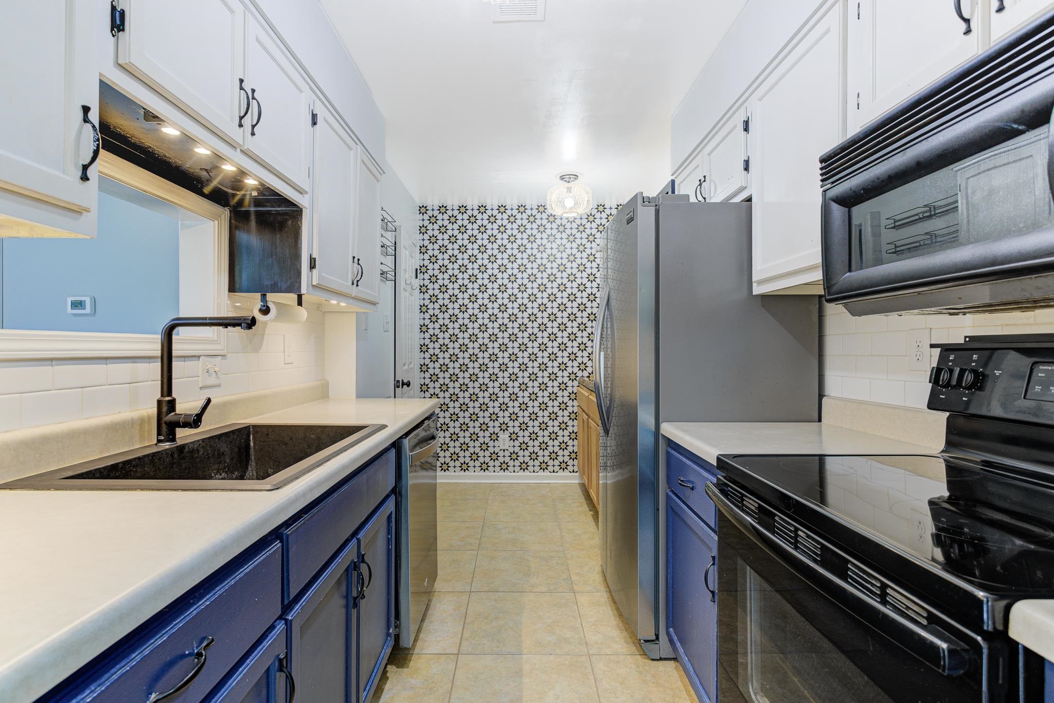 218 South Walnut Bend Road Memphis, TN 38018 - Photo 7 of 25 Kitchen with blue cabinets, black appliances, decorative backsplash, light countertops, and white cabinets