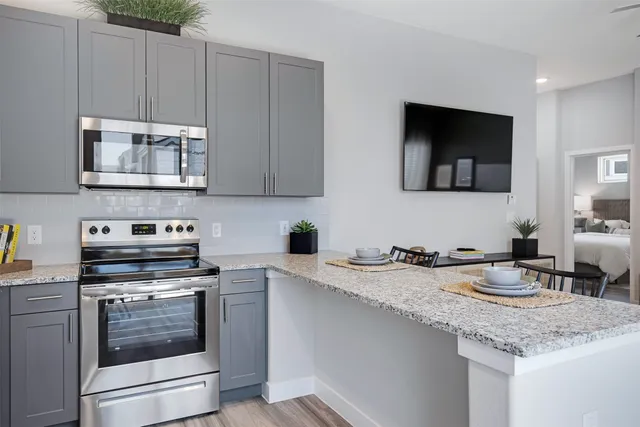 a kitchen with granite countertop a sink cabinets and stainless steel appliances