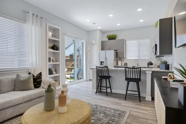 a living room with furniture a rug and kitchen view