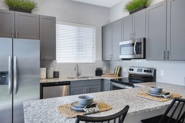 a kitchen with stainless steel appliances granite countertop a stove a sink a dining table and chairs