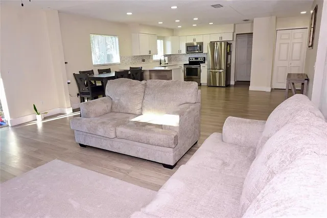 a living room with furniture and kitchen view with wooden floor
