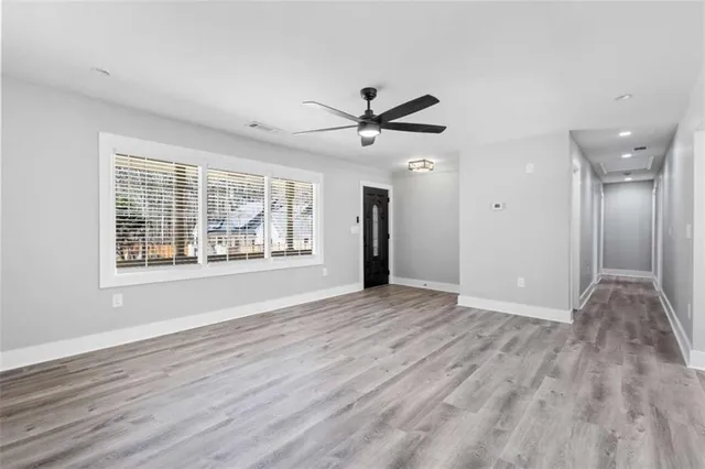 an empty room with wooden floor and windows