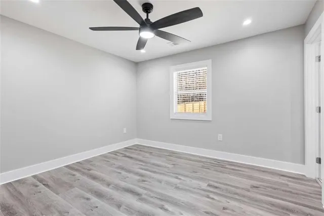 an empty room with wooden floor and a ceiling fan