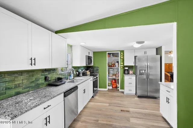 a kitchen with stainless steel appliances kitchen island granite countertop a refrigerator and a sink