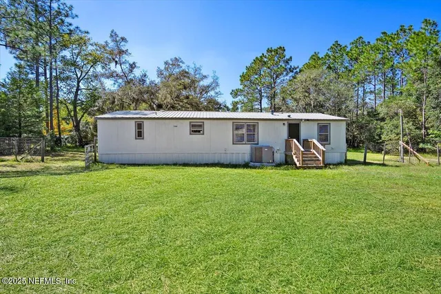 a view of a backyard with table and chairs plants and large tree