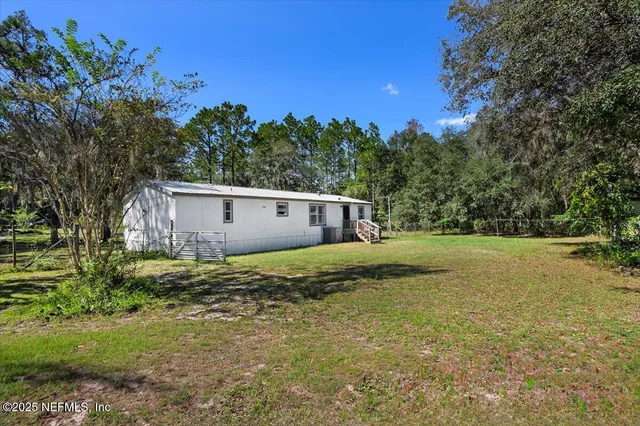 a view of a house with backyard and trees