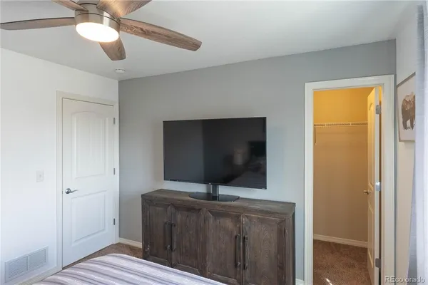 a living room with a flat screen tv and a ceiling fan