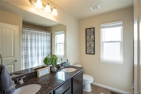 a bathroom with a granite countertop sink toilet and mirror