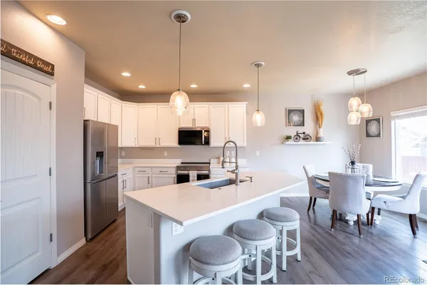 a kitchen with a dining table chairs refrigerator and microwave