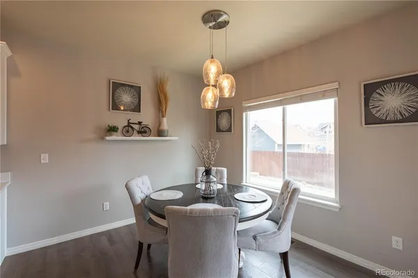 a dining room with wooden floor a chandelier a wooden table and chairs