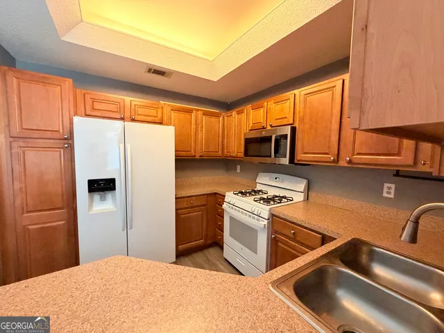 a kitchen with stainless steel appliances granite countertop a refrigerator a stove top oven a sink and dishwasher