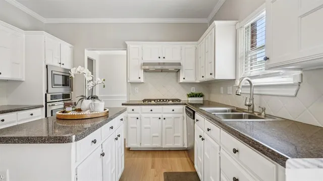 a kitchen with granite countertop a sink and white cabinets