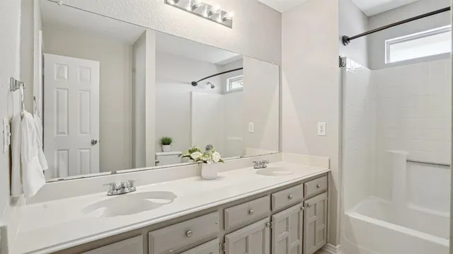 a bathroom with a sink double vanity granite tub shower and a mirror