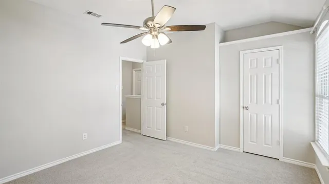 an empty room with windows and fan